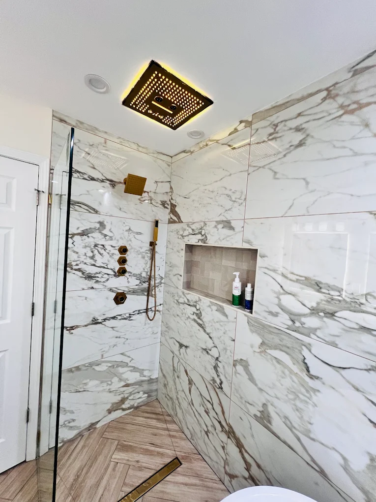 Marble & Gold Primary Bath after photo: Shower with illuminated ceiling rain head and niche