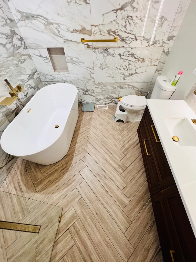 Marble & Gold Primary Bath after photo: Freestanding tub, herringbone floor, and double vanity