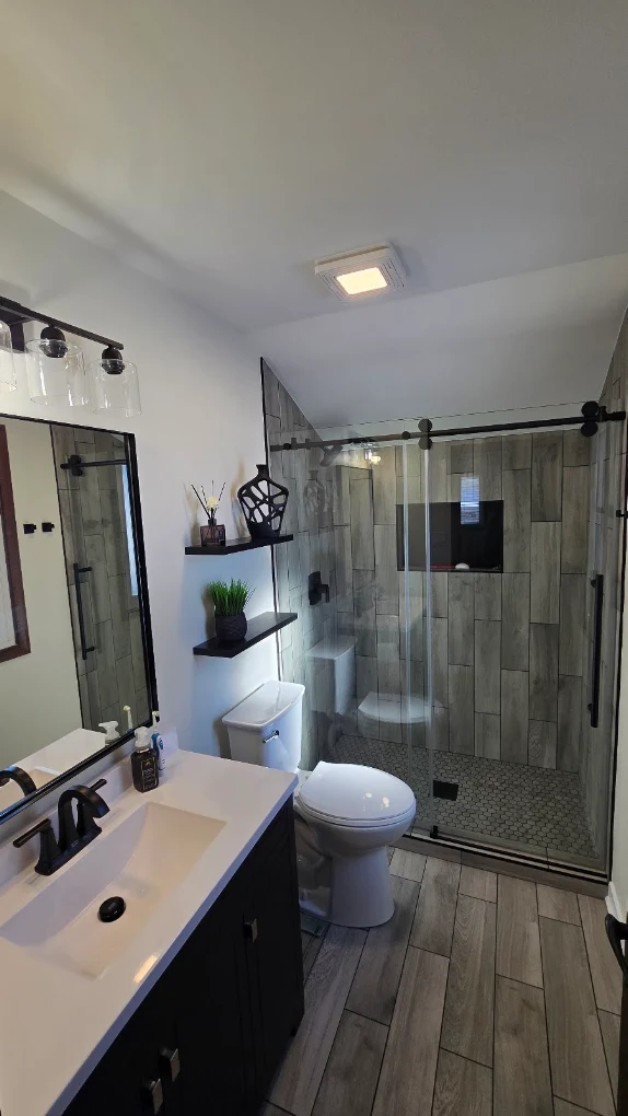 Wood-Look Tile & Matte Black after photo: Bathroom with black vanity and glass-enclosed shower