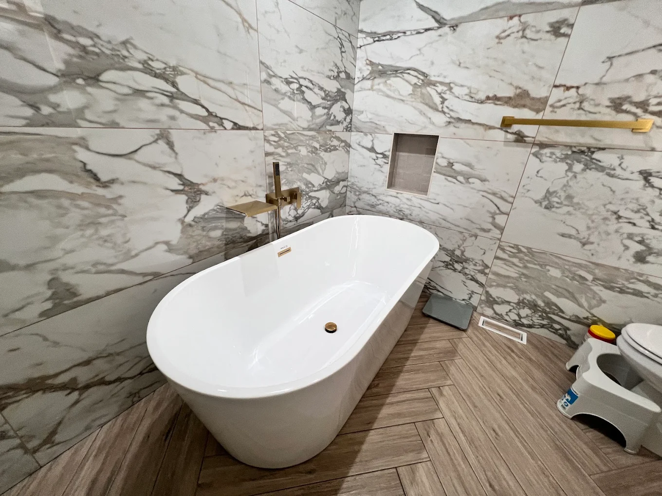 Marble & Gold Primary Bath after photo: Freestanding tub with wall-mounted gold filler