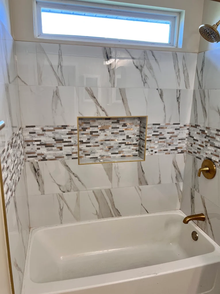 Dark Green Vanity Hall Bath after photo: Tub-shower with marble-look tile and mosaic accent band