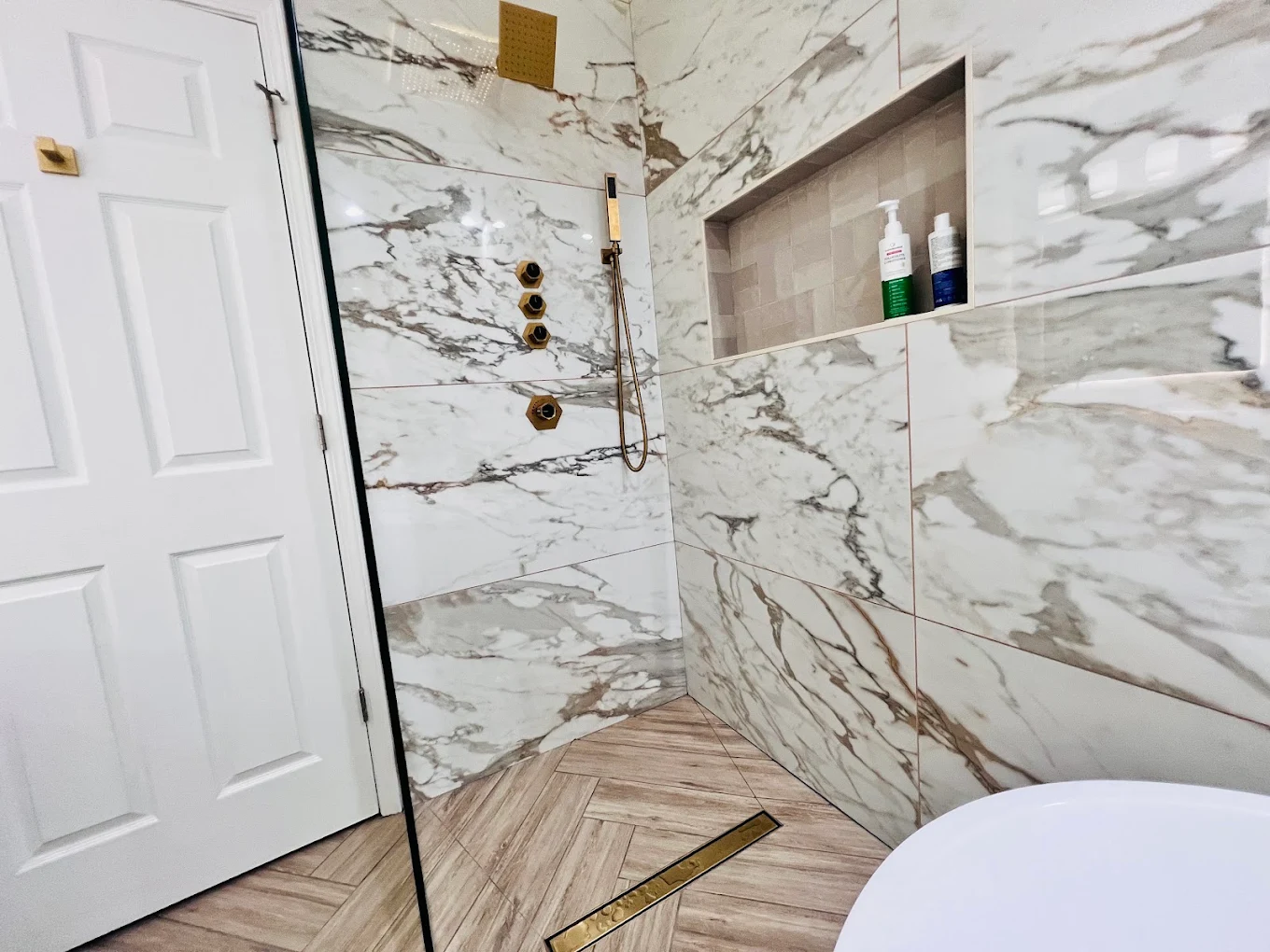 Marble & Gold Primary Bath after photo: Curbless walk-in shower with linear gold drain