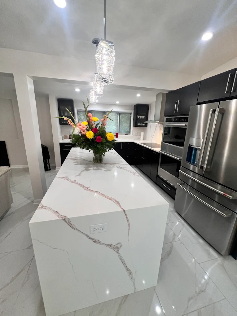 Dark Cabinetry & Marble-Look Kitchen after photo: Waterfall island and built-in appliances