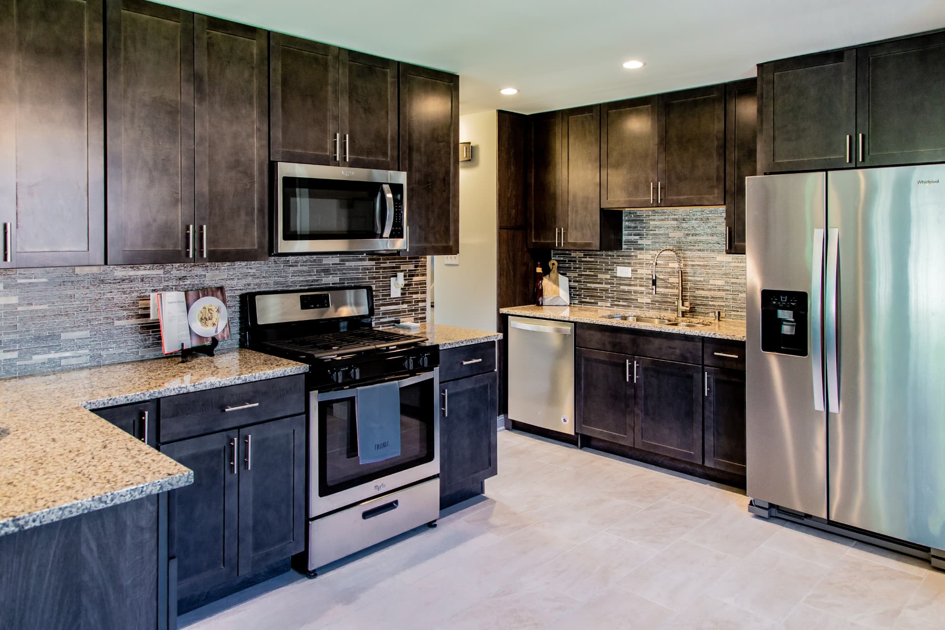 Dark Shaker Kitchen & Granite Counters after photo: Range wall with microwave, gas cooktop, and stainless appliances