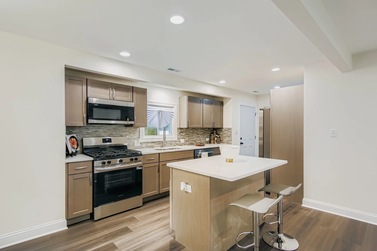 Open Kitchen & Living Room after photo: Range wall, island seating, and wide-plank flooring