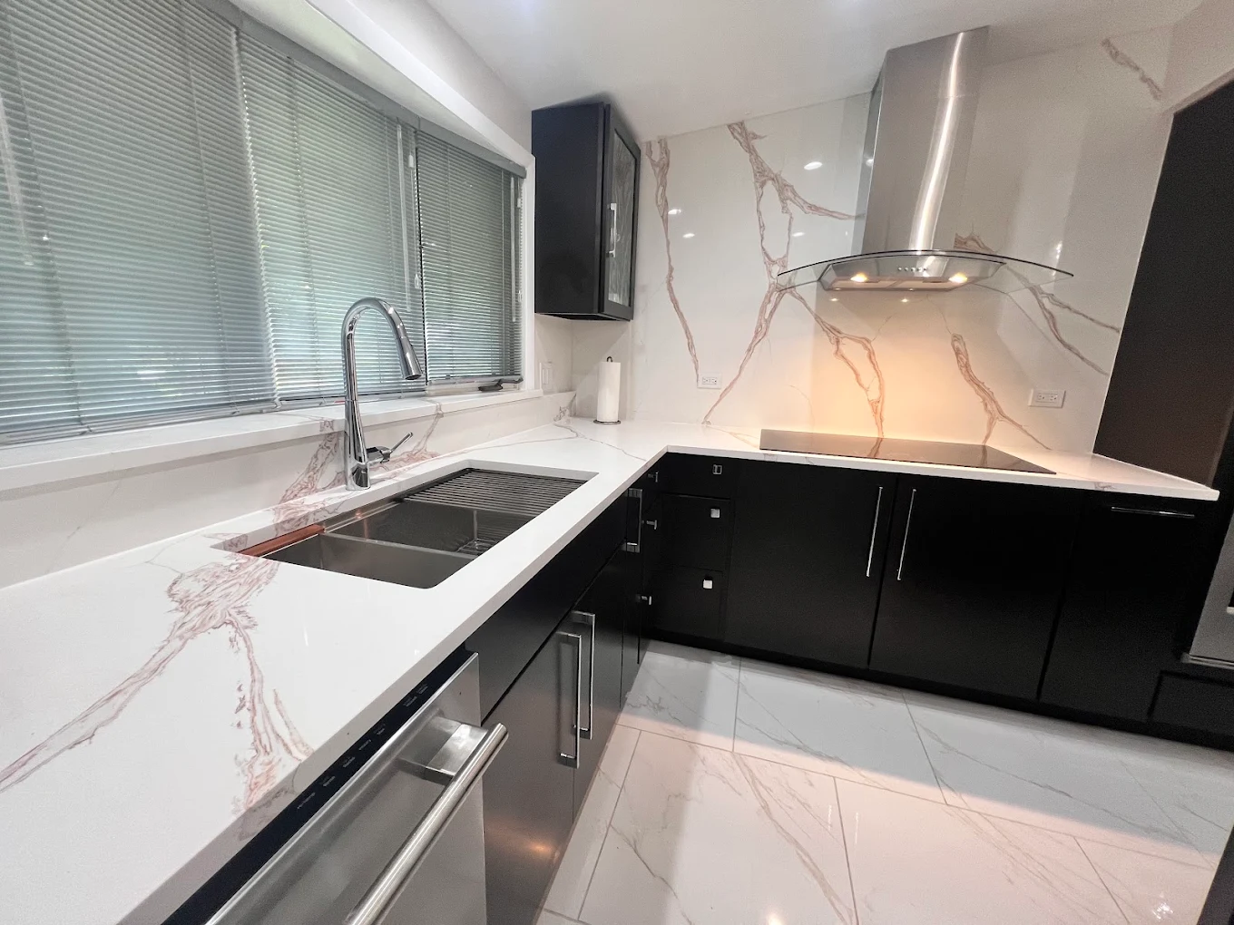 Dark Cabinetry & Marble-Look Kitchen after photo: Cooktop wall with modern stainless hood